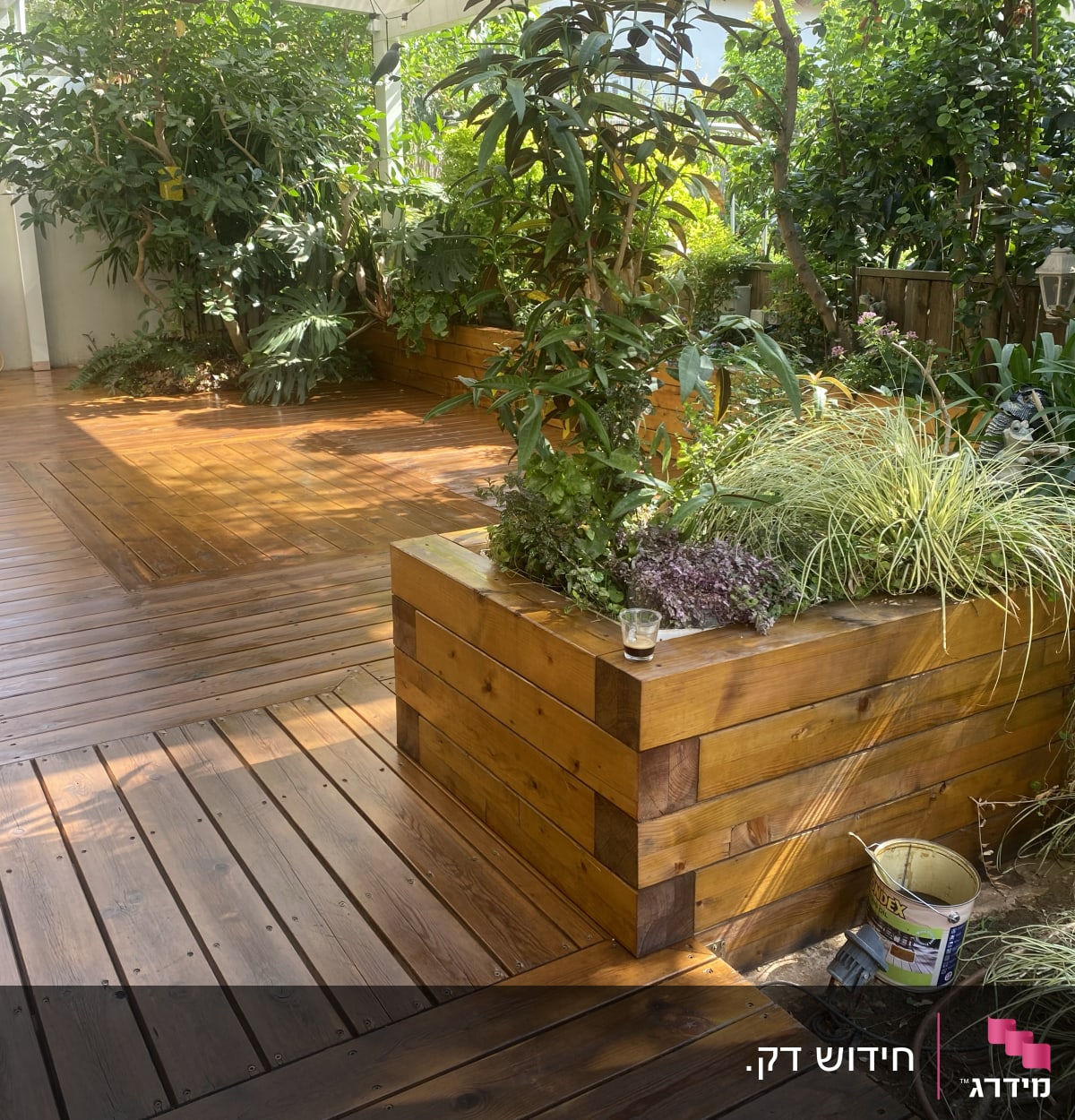 דק עץ עם אדניות עץ וצמחייה ירוקה